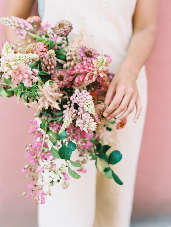 woman holding monochromatic pink bouquet in front of pink wall