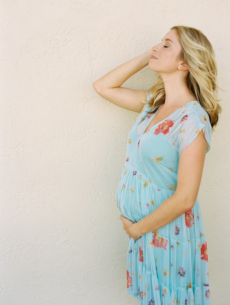 Pregnant woman in front of peach wall at Maternity Photo shoot