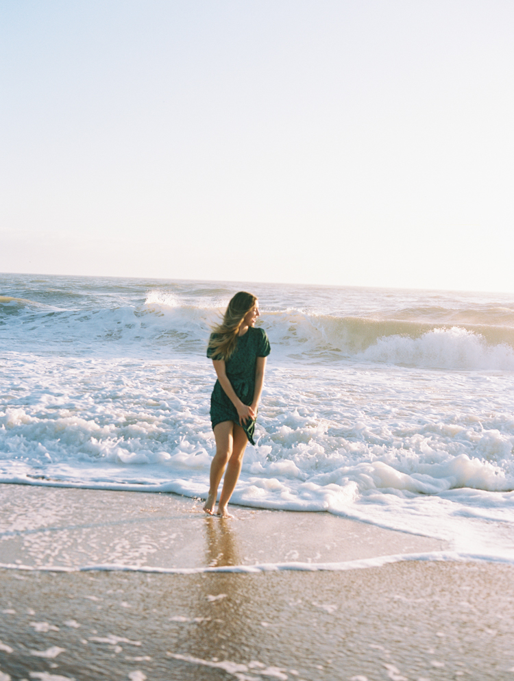 boho girl laughing and running away from ocean waves
