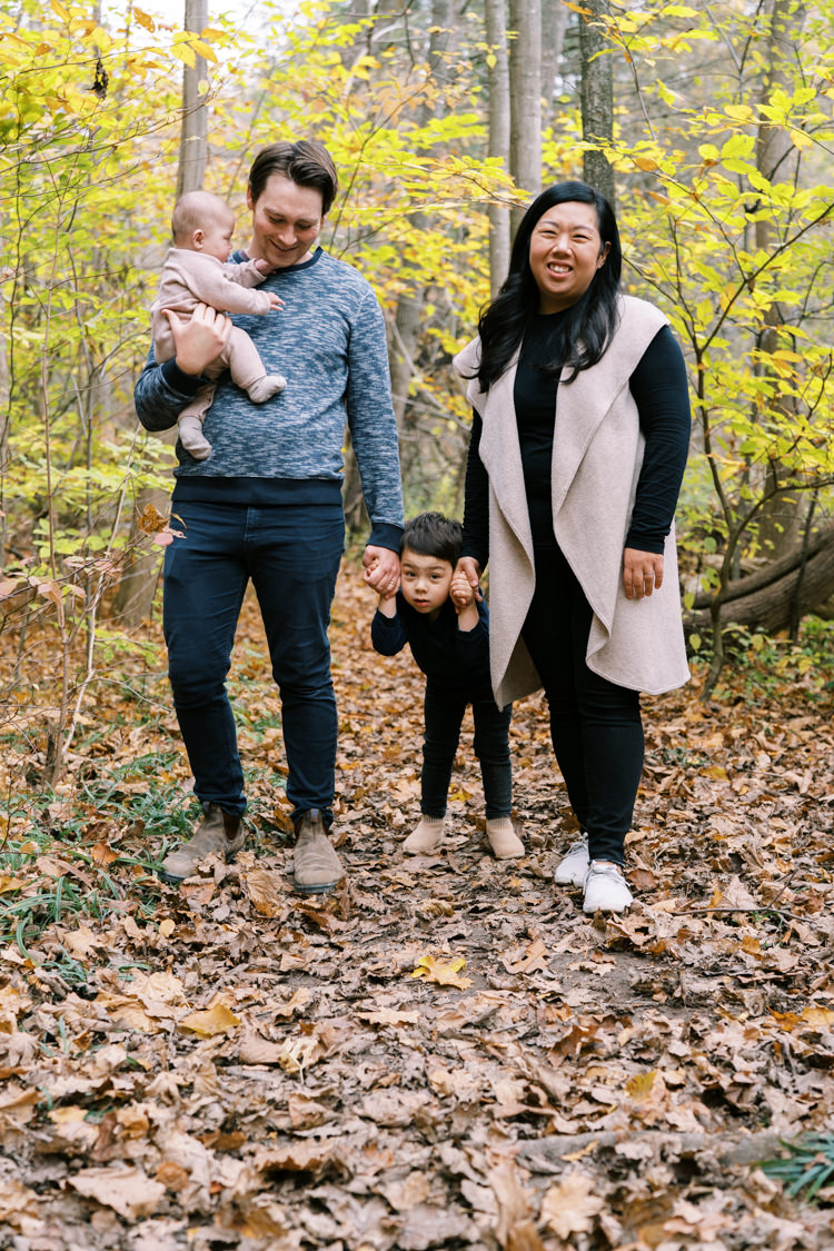 parents smiling with baby and holding their toddler's hands in halton hills forest