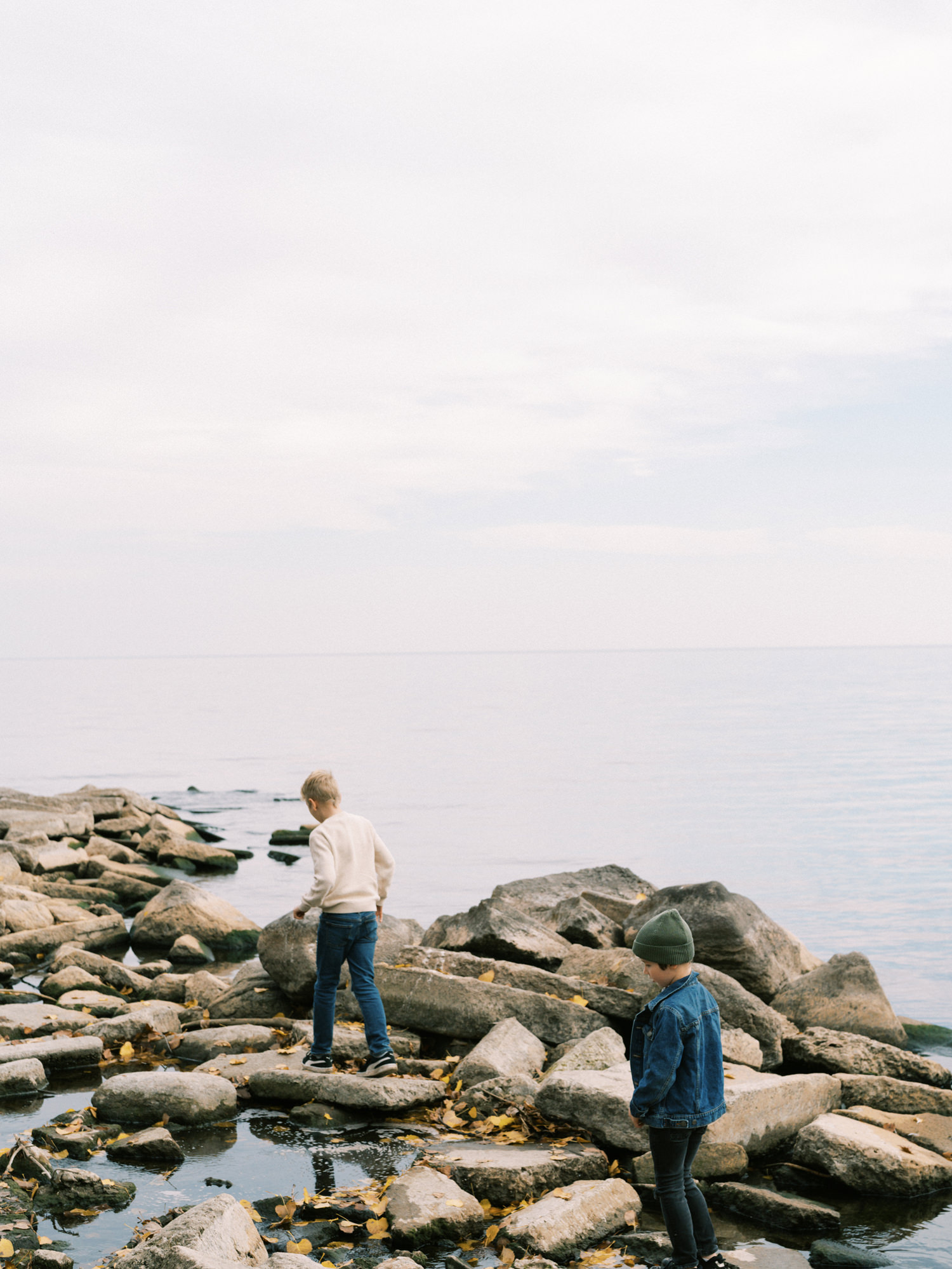boys climbing around rocks in lake ontario in mississauga