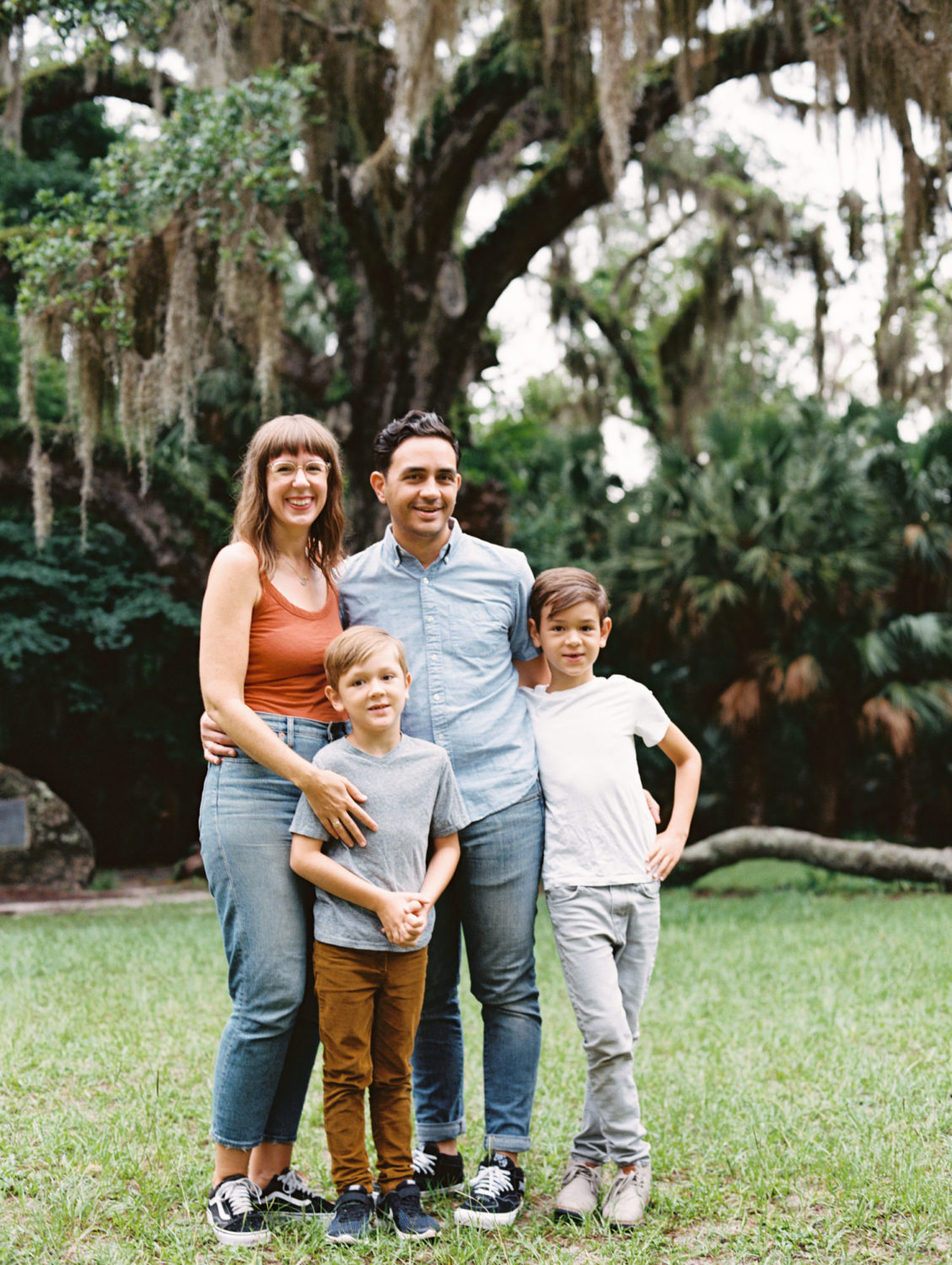 Family of four standing in front of huge live oak tree in the summer