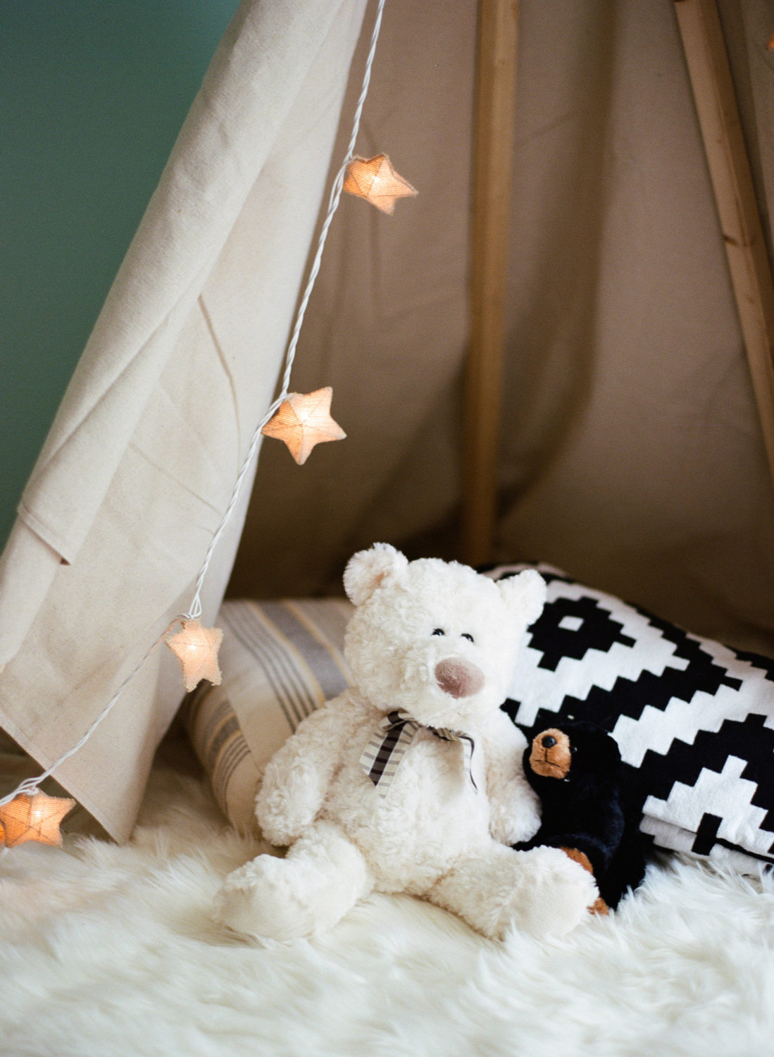 white and black teddy bears sitting on the ground inside a child's play tent with star lights