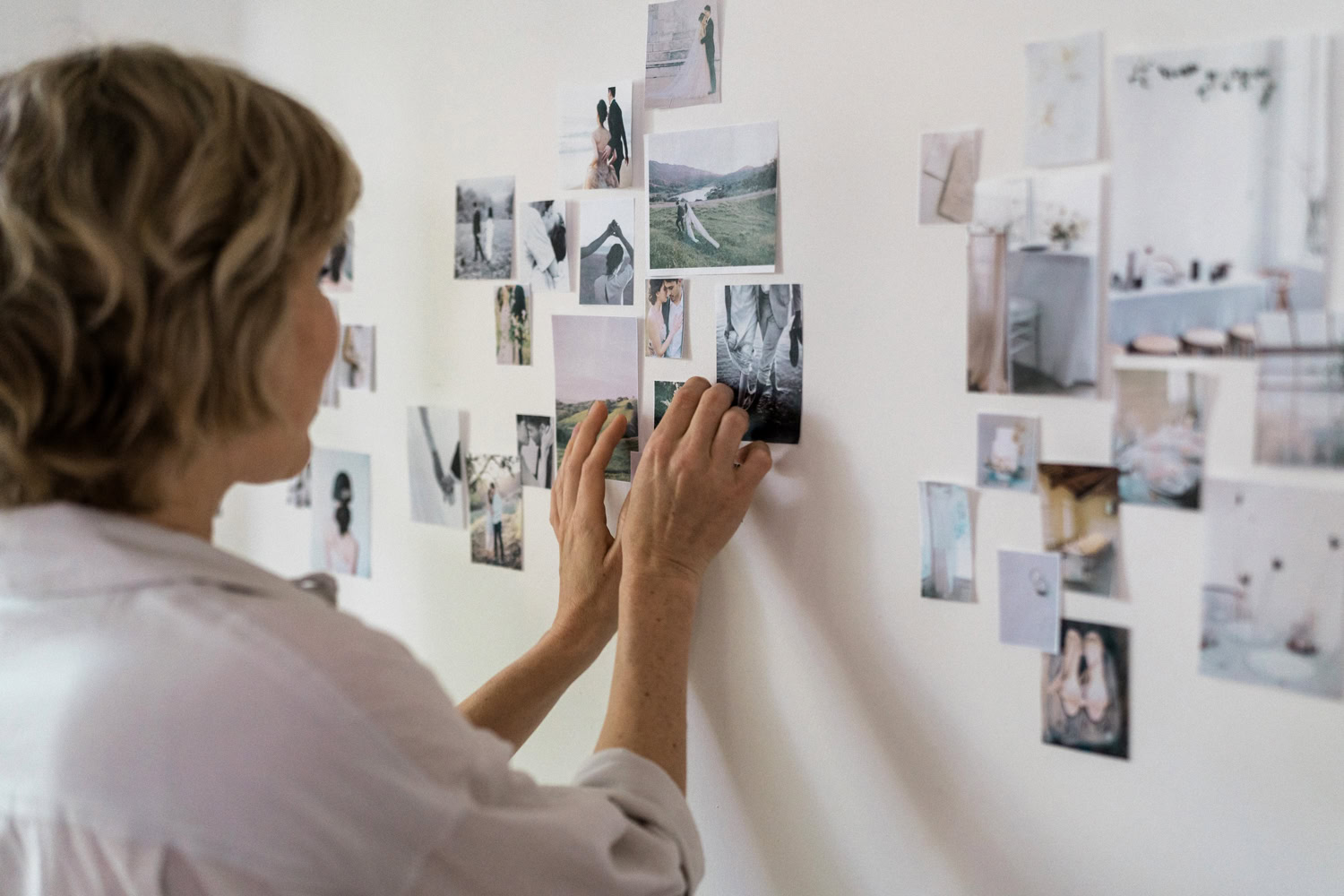 woman with short blonde hair and white shirt taping inspiration photos to a white wall