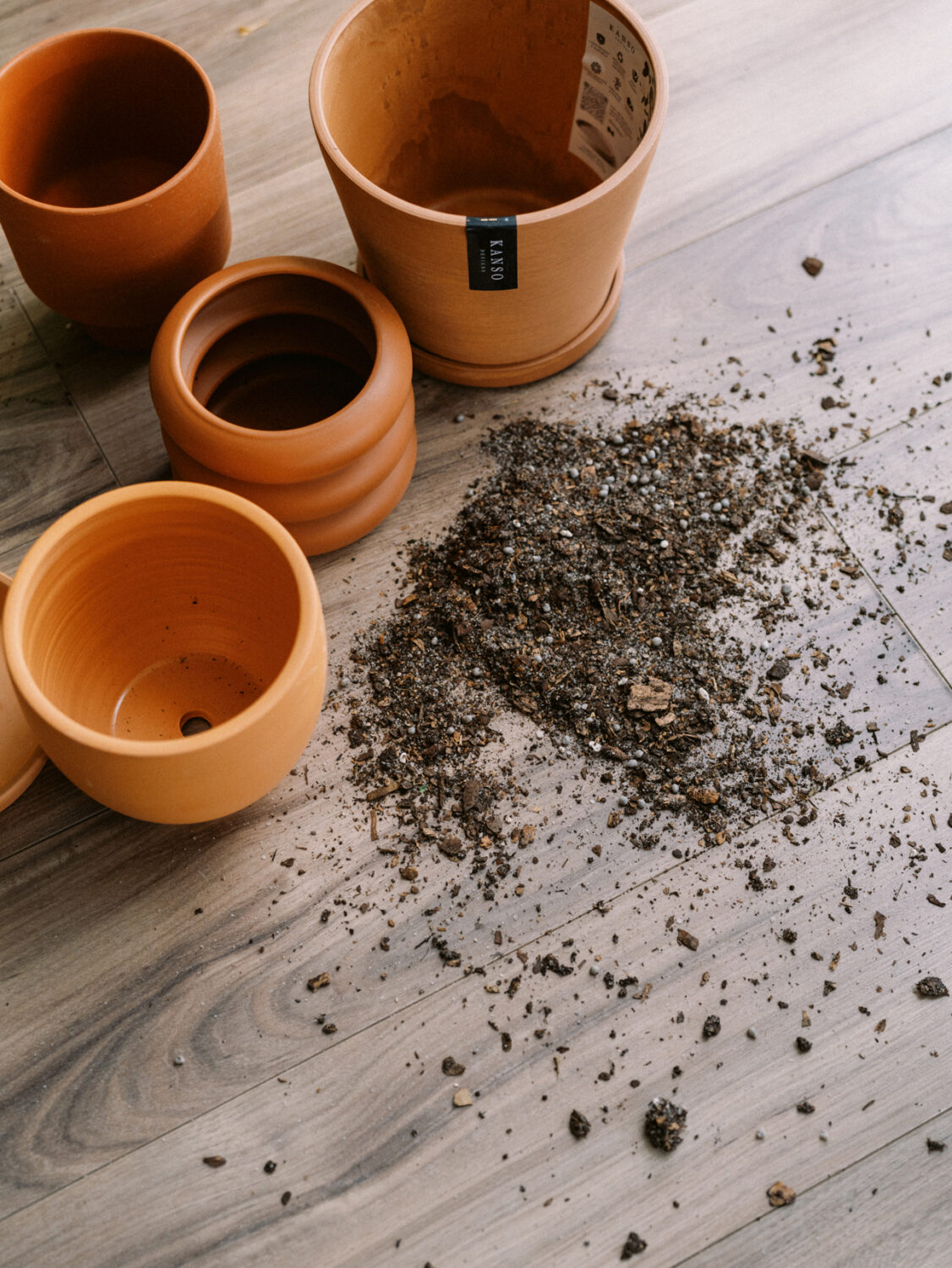 empty terracotta plant pots on a brown floor with dirt spilled in front of them