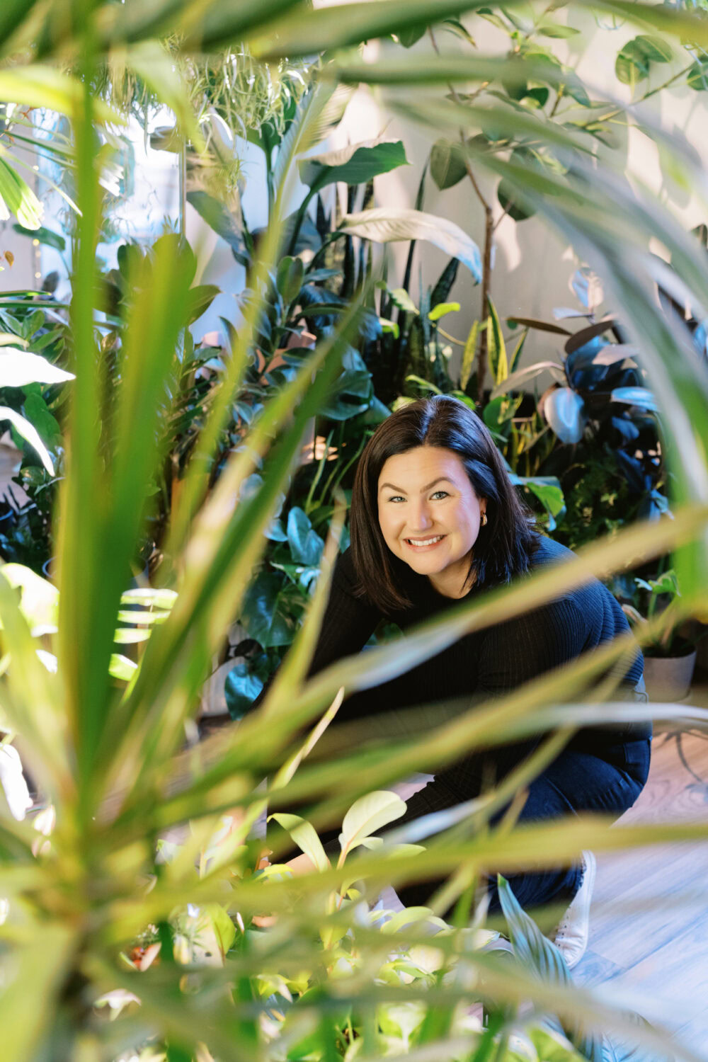 woman looking up and smiling while kneeling to water plants