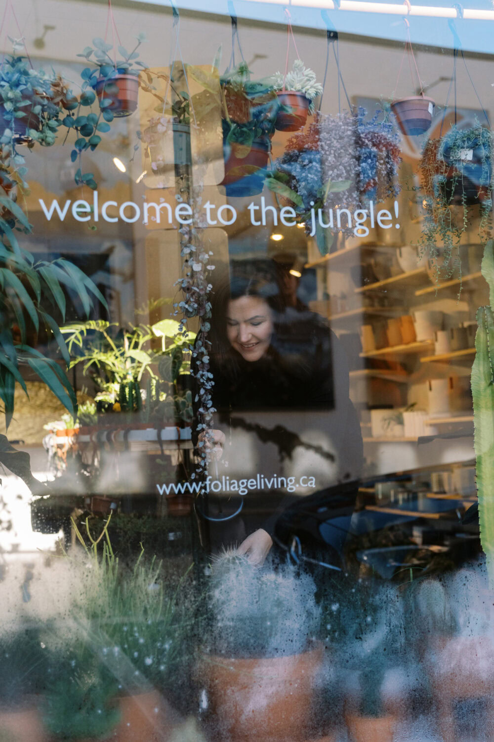 business owner tending to her plants seen through the front window of her store