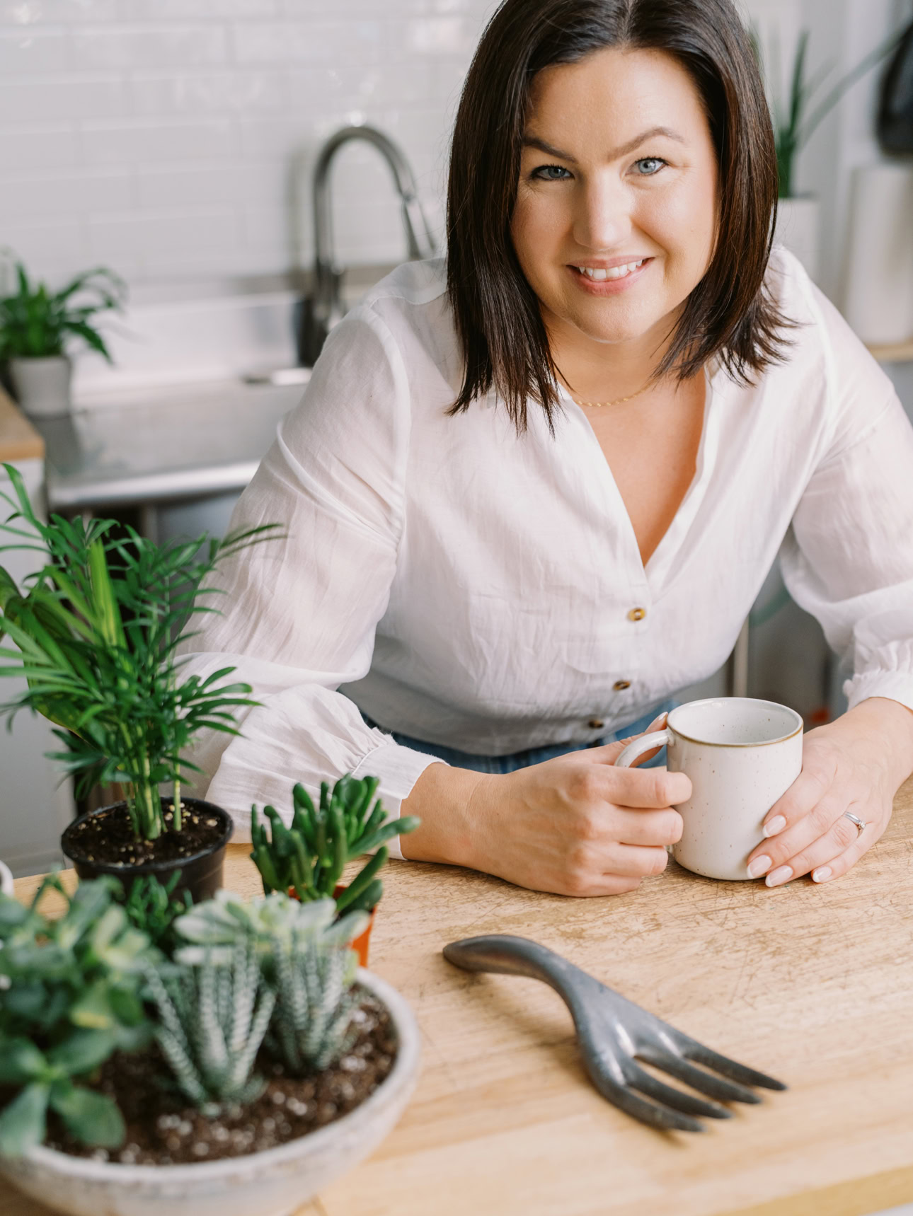 Shop owner sitting at a wood counter holding her coffee and smiling