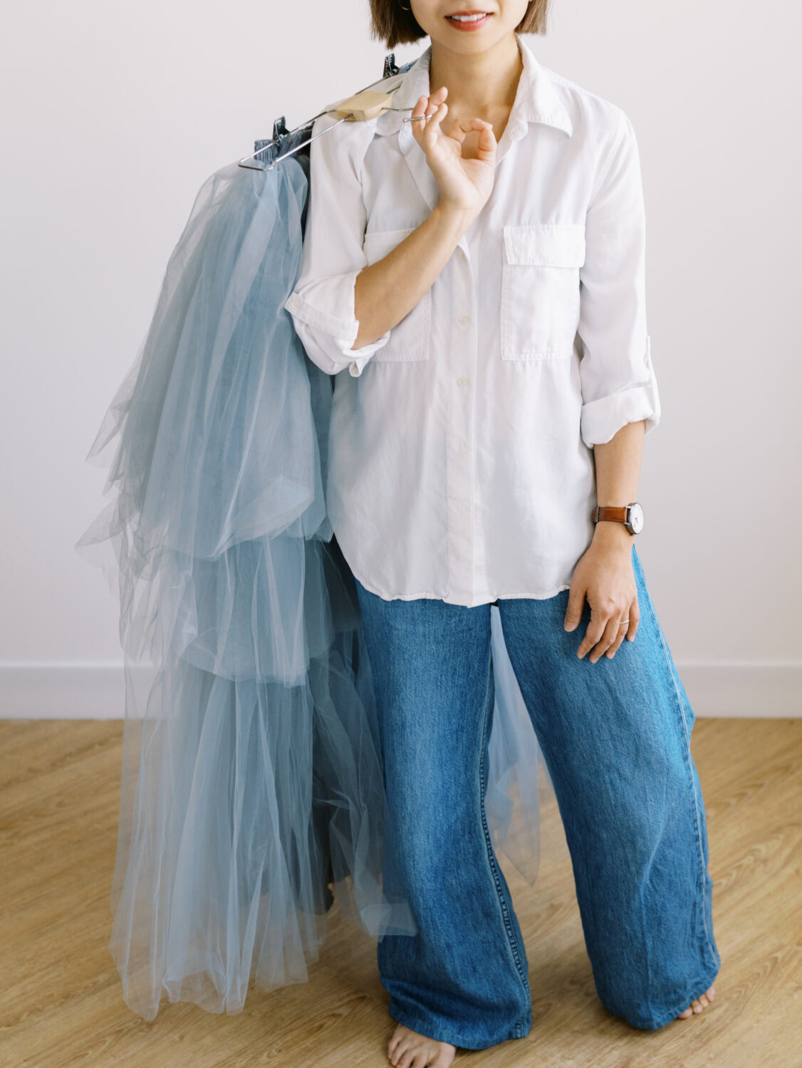 person standing holding a blue tulle skirt over her shoulder