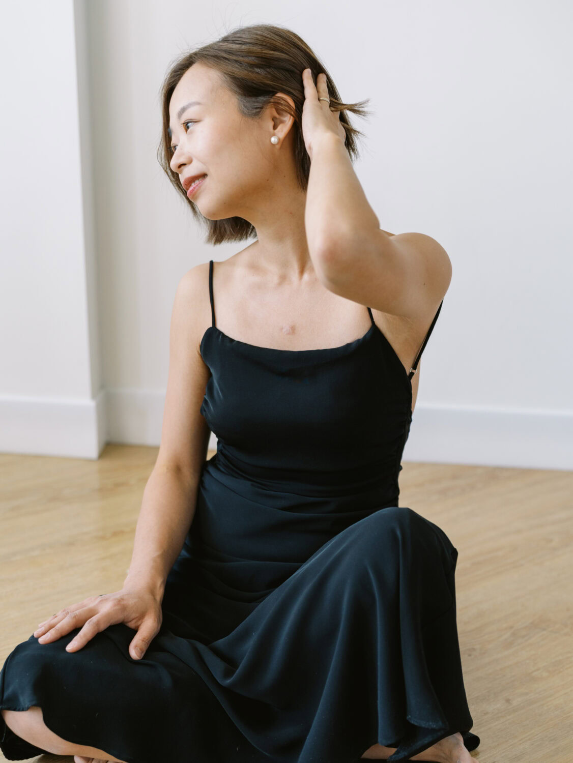 woman with short brown hair sitting on the floor in a black dress at a Toronto photo studio