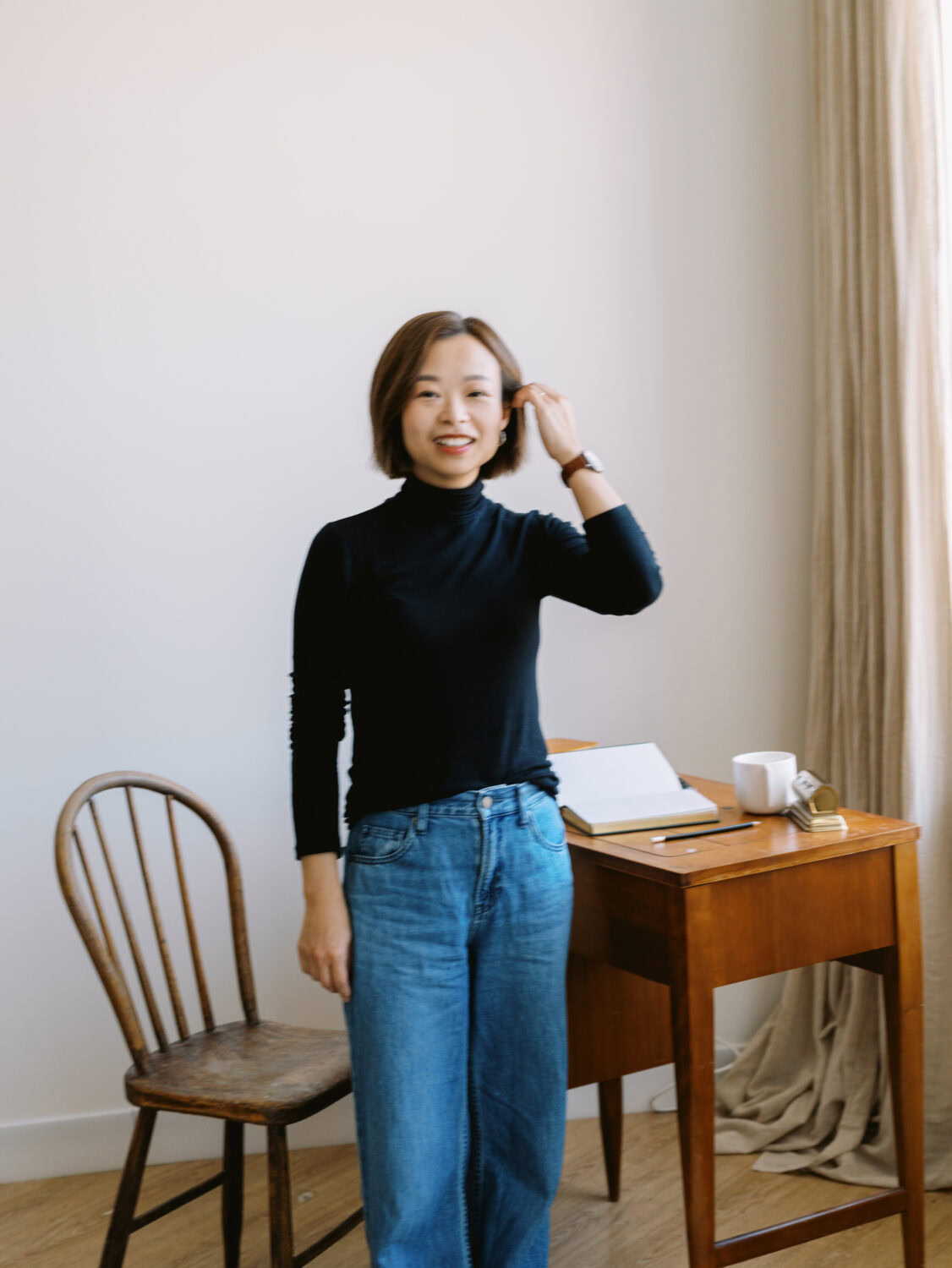 writer in a black top and blue jeans standing from her desk in a markham photo studio